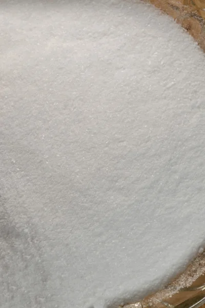 Гранулированный белый сахар крупным планом в стекле — стоковое фото