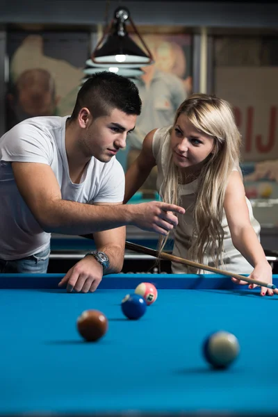 Mann lehrt Frau, wie man Pool spielt — Stockfoto