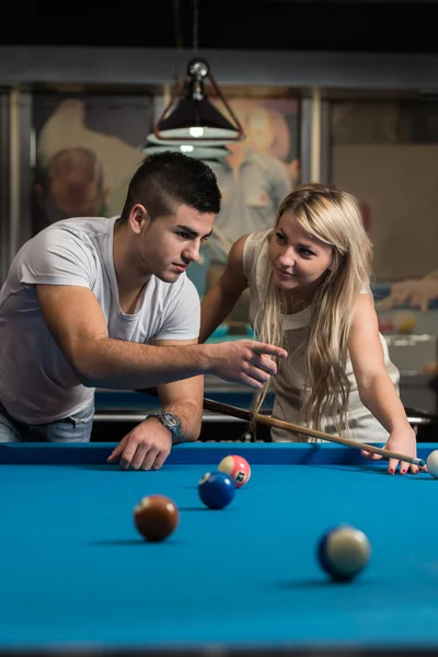 Mann lehrt Frau, wie man Pool spielt — Stockfoto