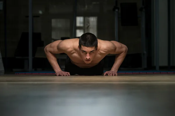 Jonge man doen pers ups in gym — Stockfoto