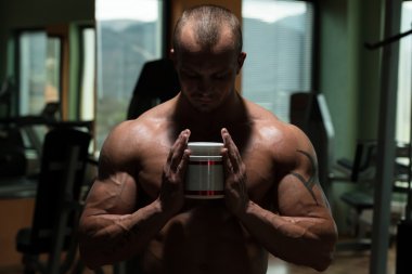 Bodybuilder Posing With Supplements For Copy Space clipart