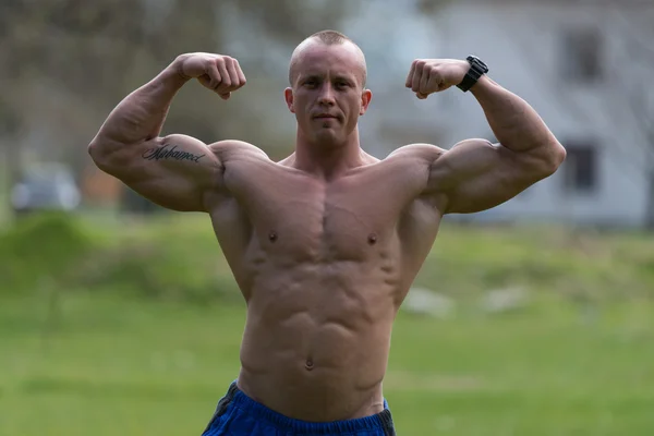 Bodybuilder posiert im Park mit doppeltem Bizeps — Stockfoto