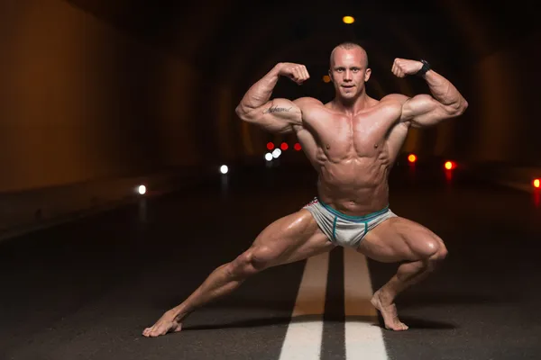 Bodybuilder Performing Front Double Biceps Poses In Tunnel — Stock Photo, Image