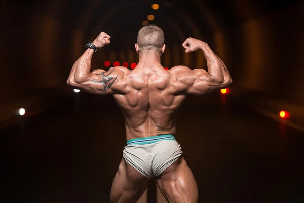 Bodybuilder Performing Rear Double Biceps Poses In Tunnel — Stock Photo, Image