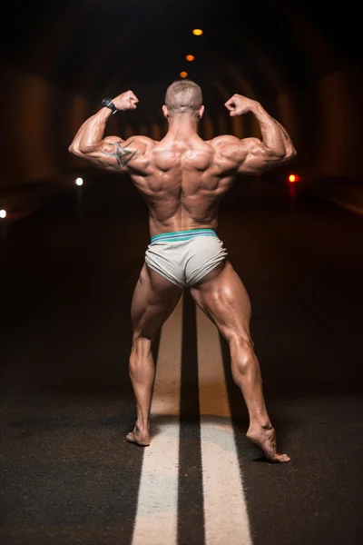 Bodybuilder uitvoeren van achterste dubbele biceps vormt in tunnel — Stockfoto