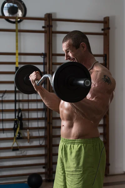 Culturista ejercitando bíceps con barra —  Fotos de Stock