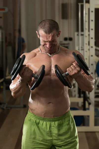 Joven haciendo ejercicio Biceps Dumbbell Concentration Curls —  Fotos de Stock