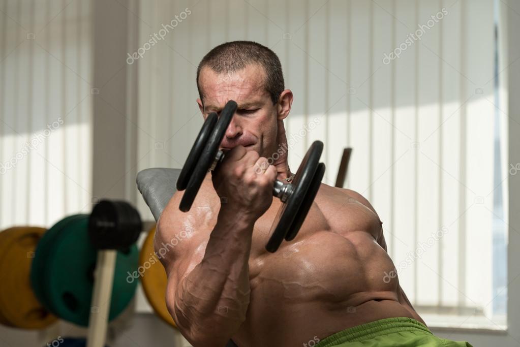 Bodybuilder Working Out Biceps In A Health Club