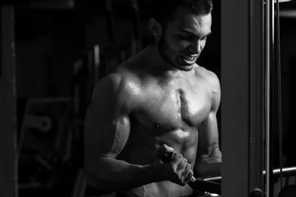 Joven ejercitando bíceps en un gimnasio — Foto de Stock