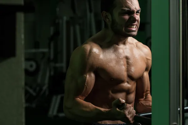 Młody człowiek ćwiczeń bicepsów w siłowni — Zdjęcie stockowe