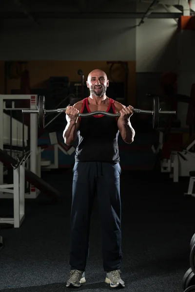 Mogna kroppsbyggare tränar biceps med skivstång — Stockfoto