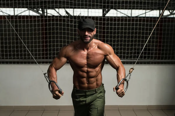 Gespierde bodybuilder presterende kabel crossover — Stockfoto