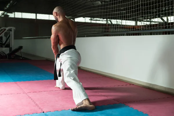 Karate hombre en un kimono limbering hasta —  Fotos de Stock