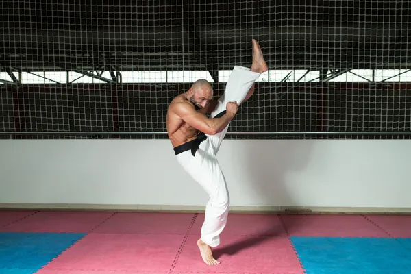 Volwassen man maakt een kick in kimono — Stockfoto