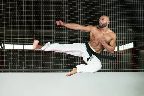 Volwassen man maakt een kick in kimono — Stockfoto