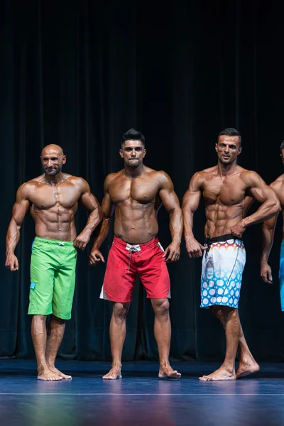 Mens kroppsbyggnad poserar under en bodybuilding tävling — Stockfoto