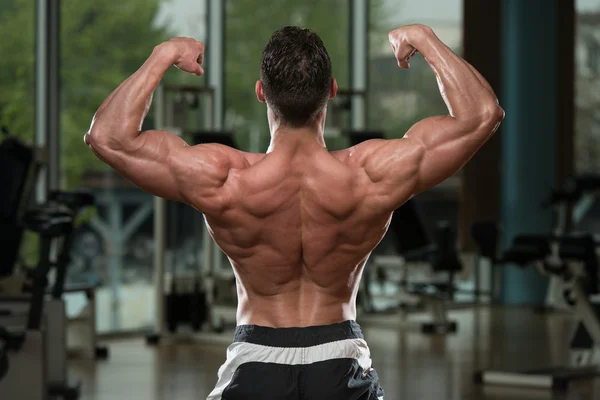 Bodybuilder presterende achterste dubbele biceps vormen — Stockfoto