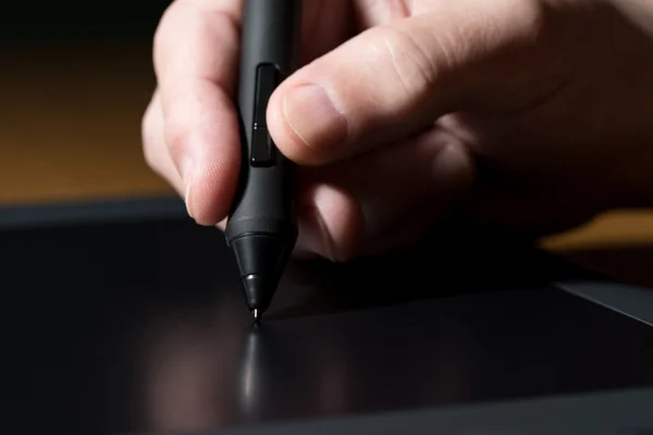 Mão segurando caneta gráfica sobre mesa — Fotografia de Stock