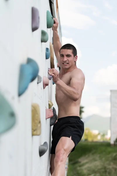 Jovem pendurado de uma parede de escalada — Fotografia de Stock