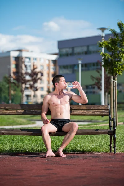 Jeune homme musculaire buvant une bouteille d'eau — Photo