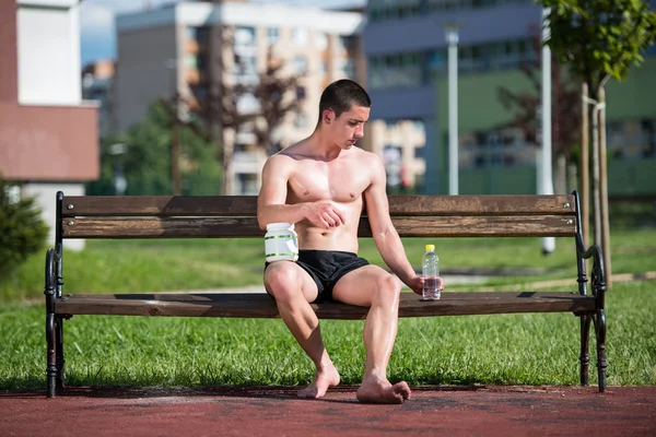 年轻的肌肉男，喝一瓶水 — 图库照片