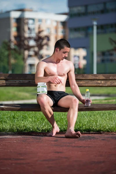 Jeune homme musculaire buvant une bouteille d'eau — Photo