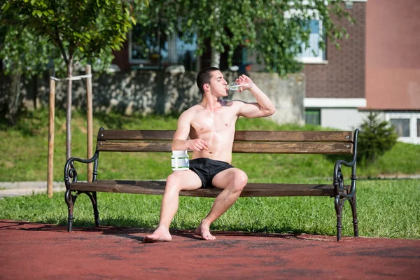 Młody człowiek mięśni butelkę wody do picia — Zdjęcie stockowe