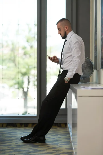 Hombre de negocios mensajes de texto en el teléfono celular en la oficina moderna —  Fotos de Stock