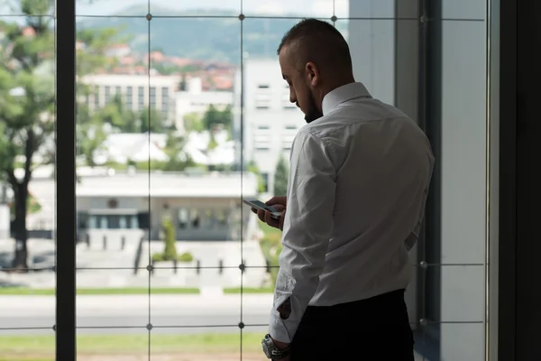 Homem de negócios mensagens de texto no celular no escritório moderno — Fotografia de Stock