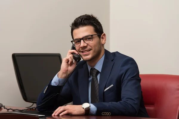 Бизнесмен разговаривает по телефону и пользуется компьютером — стоковое фото