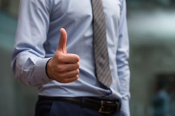 Mänsklig hand visar tummen på förgrunden — Stockfoto