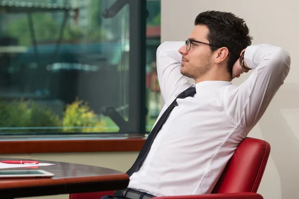 Jovem empresário relaxa sentado no escritório — Fotografia de Stock