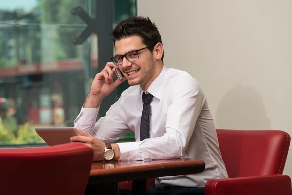 Empresario hablando por teléfono y usando tableta — Foto de Stock