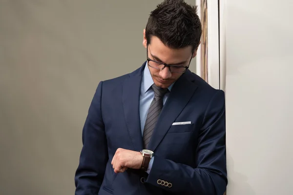 Hombre de negocios guapo comprobando el tiempo en su reloj —  Fotos de Stock