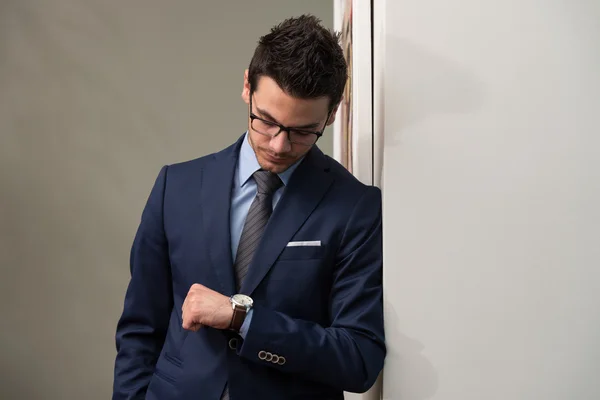 Hombre de negocios guapo comprobando el tiempo en su reloj —  Fotos de Stock