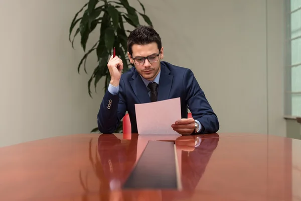 Retrato del atractivo hombre de negocios leyendo papel en la oficina — Foto de Stock