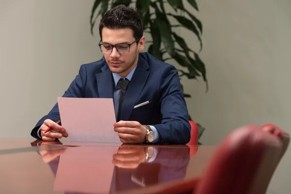 Geschäftsmann sitzt am Schreibtisch und unterschreibt einen Vertrag — Stockfoto