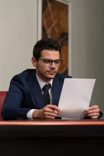 Jovem empresário no escritório olhando para o papel — Fotografia de Stock