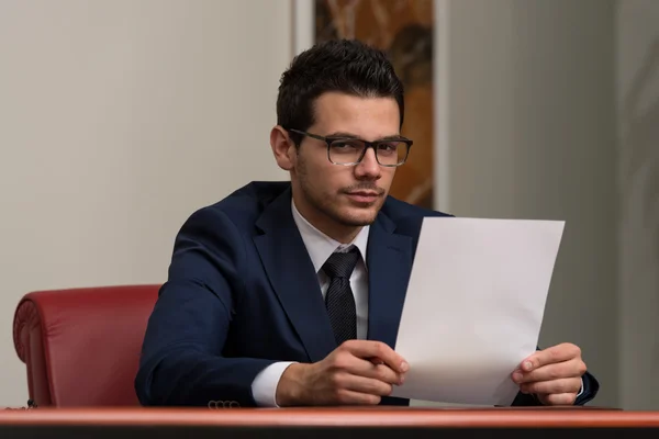 Jovem empresário no escritório olhando para o papel — Fotografia de Stock