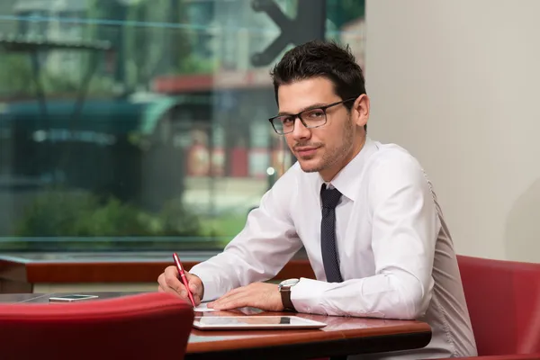 Geschäftsmann sitzt am Schreibtisch und unterschreibt einen Vertrag — Stockfoto