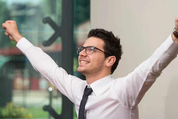 Erfolgreicher Geschäftsmann mit erhobenen Armen im Büro — Stockfoto