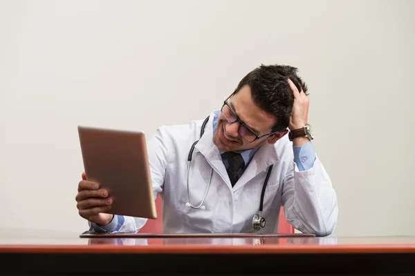 Überlasteter Arzt sitzt am Schreibtisch — Stockfoto