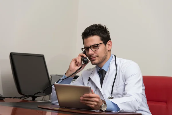 Läkare pratar på telefon och dator — Stockfoto