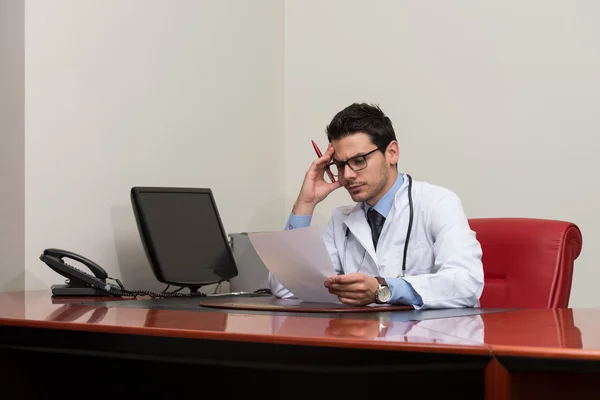 Jovem médico no escritório olhando para o papel — Fotografia de Stock