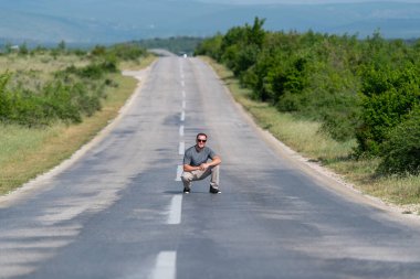 Caddedeki otoyolda güçlü çömelmiş ve poz veren yakışıklı adam.