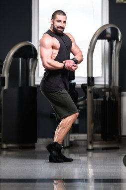 Yakışıklı Genç Adam Spor Salonunda Güçlü Duruyor ve Kaslarını Geriyor - Kas Atletik Vücut Geliştirici Spor Sonrası Spor Pozisyonu