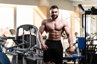Spor salonu ve kasların esneme - güçlü ayakta sağlıklı genç adam kaslı atletik vücut Fitness Model çalışmaları sonra poz