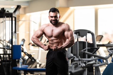 Spor salonu ve kasların esneme - güçlü ayakta sağlıklı genç adam kaslı atletik vücut Fitness Model çalışmaları sonra poz