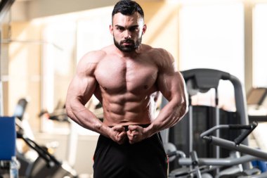 Spor salonu ve kasların esneme - güçlü ayakta sağlıklı genç adam kaslı atletik vücut Fitness Model çalışmaları sonra poz
