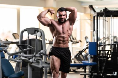 Spor salonu ve kasların esneme - güçlü ayakta sağlıklı genç adam kaslı atletik vücut Fitness Model çalışmaları sonra poz